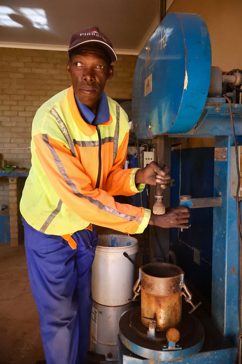 Technician operating a compaction-related soil testing machine