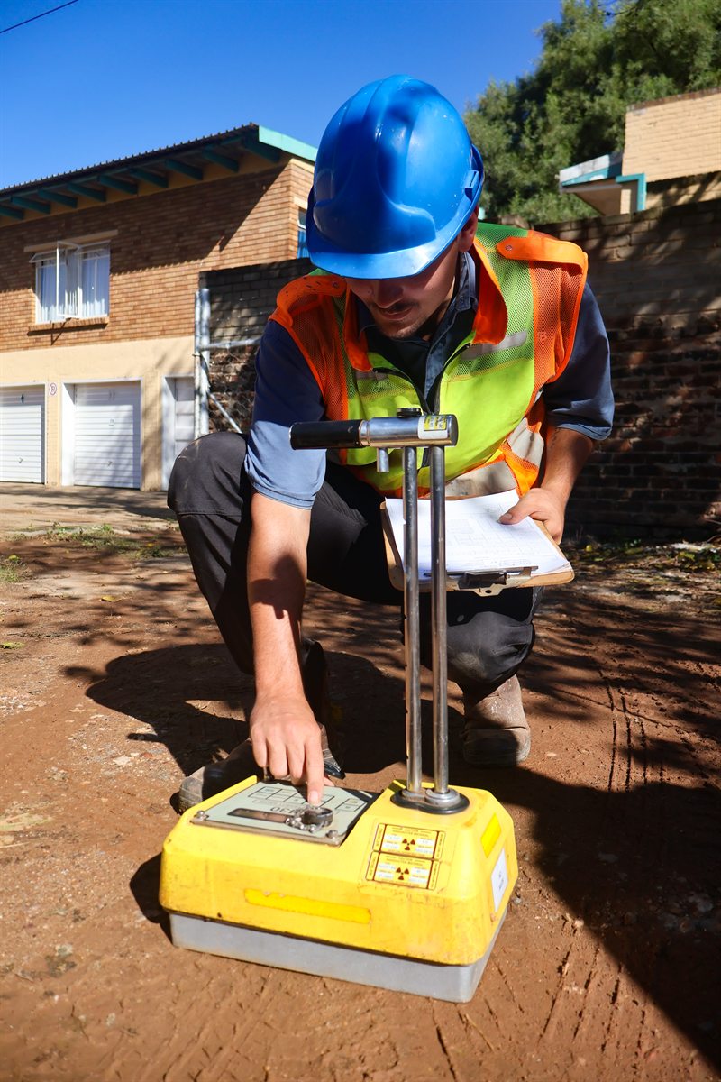 Technician operating compaction testing equipment on site